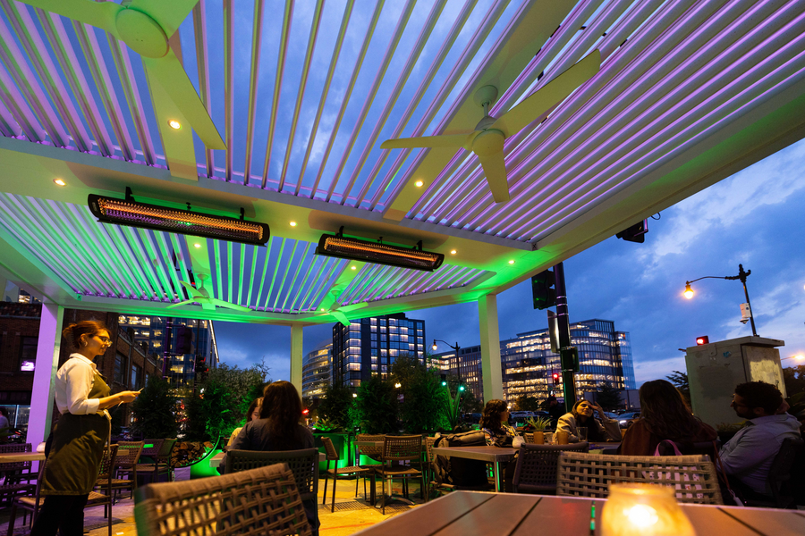 The patio of an outdoor restaurant in the city at eveningtime.