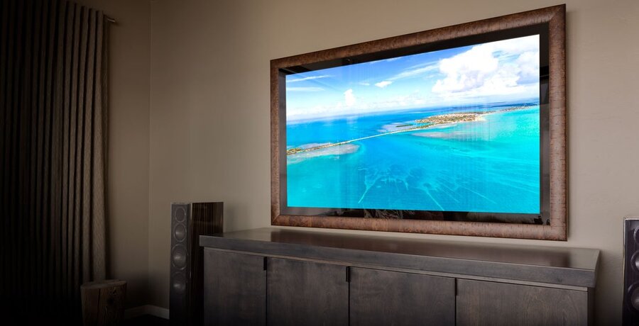A Séura mirror TV above a counter and cabinet doors, with speakers on either side of the cabinets.