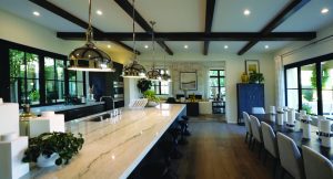 A kitchen and living area features modern recessed lighting and pendants over a large island.