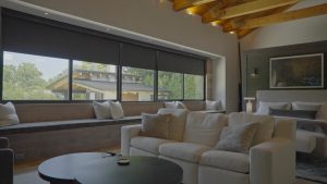 Dark motorized shades lowered halfway on a living room’s windows.