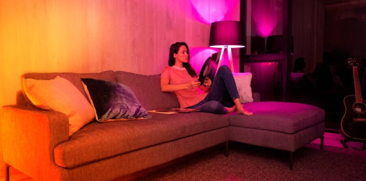 A woman sitting on a couch with various lighting colors coming from her fixtures.