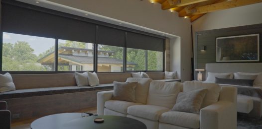 Dark motorized shades lowered halfway on a living room’s windows.