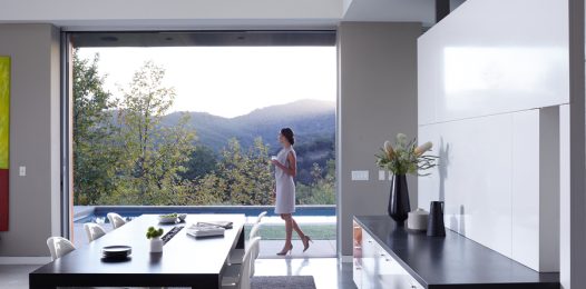 A woman walks through her terrace and into her home while looking at the landscape.