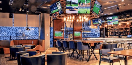 A restaurant with several tables, pendant lights, and in-ceiling Focal speakers.