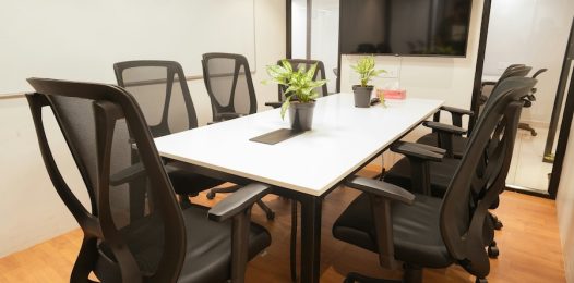 corporate meeting room with various lighting fixtures and an on-wall TV display for videoconferencing.