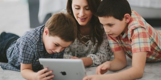 A woman with two boys looking at an iPad.