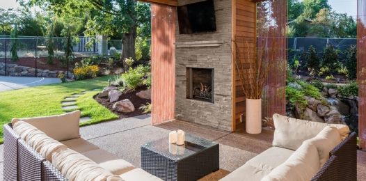 An outdoor patio area featuring an outdoor TV, seating, and motorized patio shades.