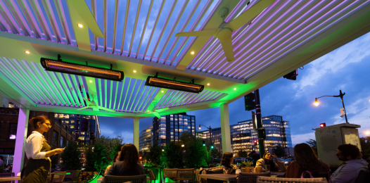 The patio of an outdoor restaurant in the city at eveningtime.