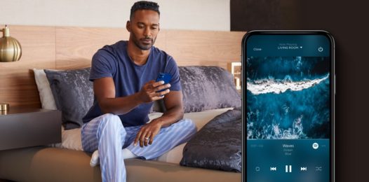 person sitting on bed while holding smartphone, and a closeup view of screen showing media selections