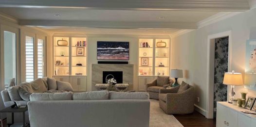 A living room with ambient lighting and accent lighting that highlights the bookshelves.